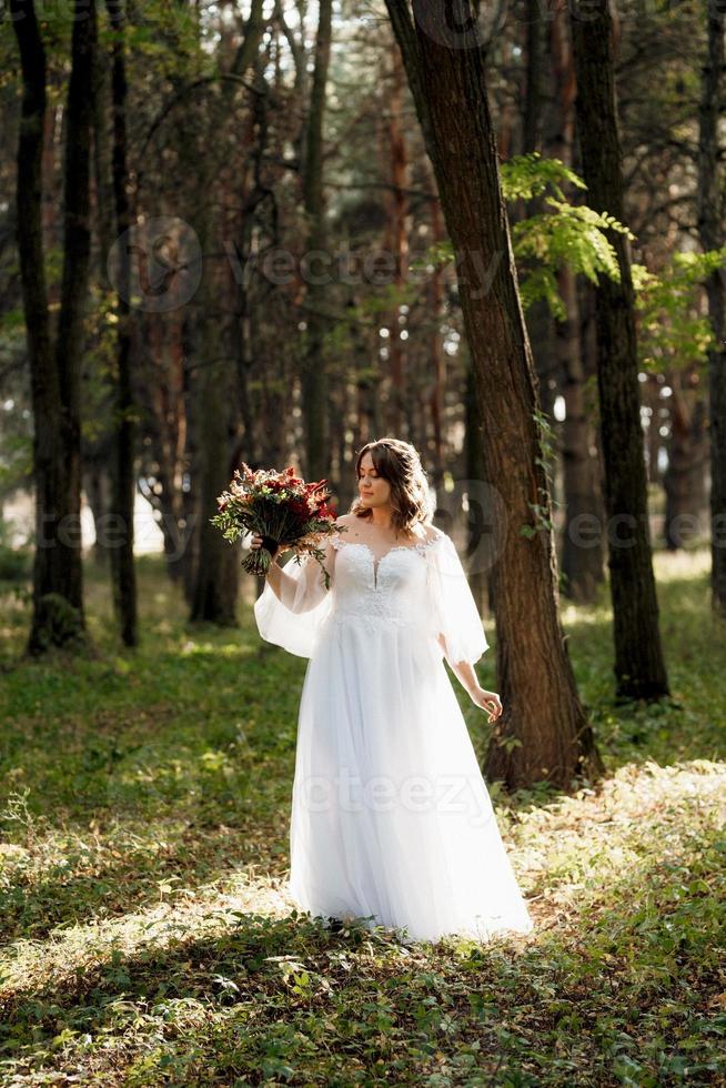 garota em um vestido de noiva na floresta de outono foto