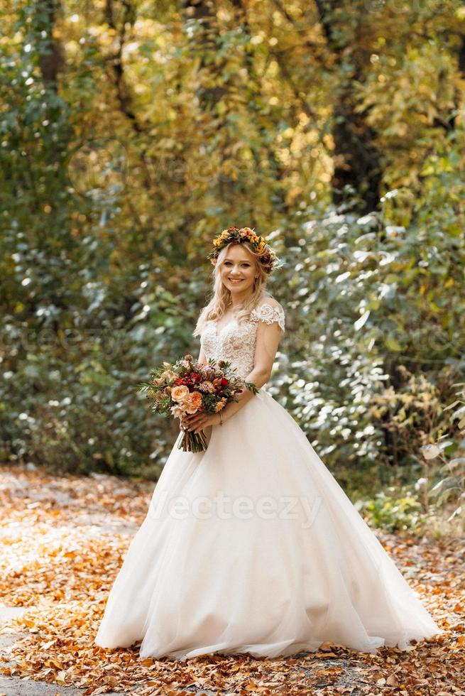 menina loira com um vestido de noiva na floresta de outono foto