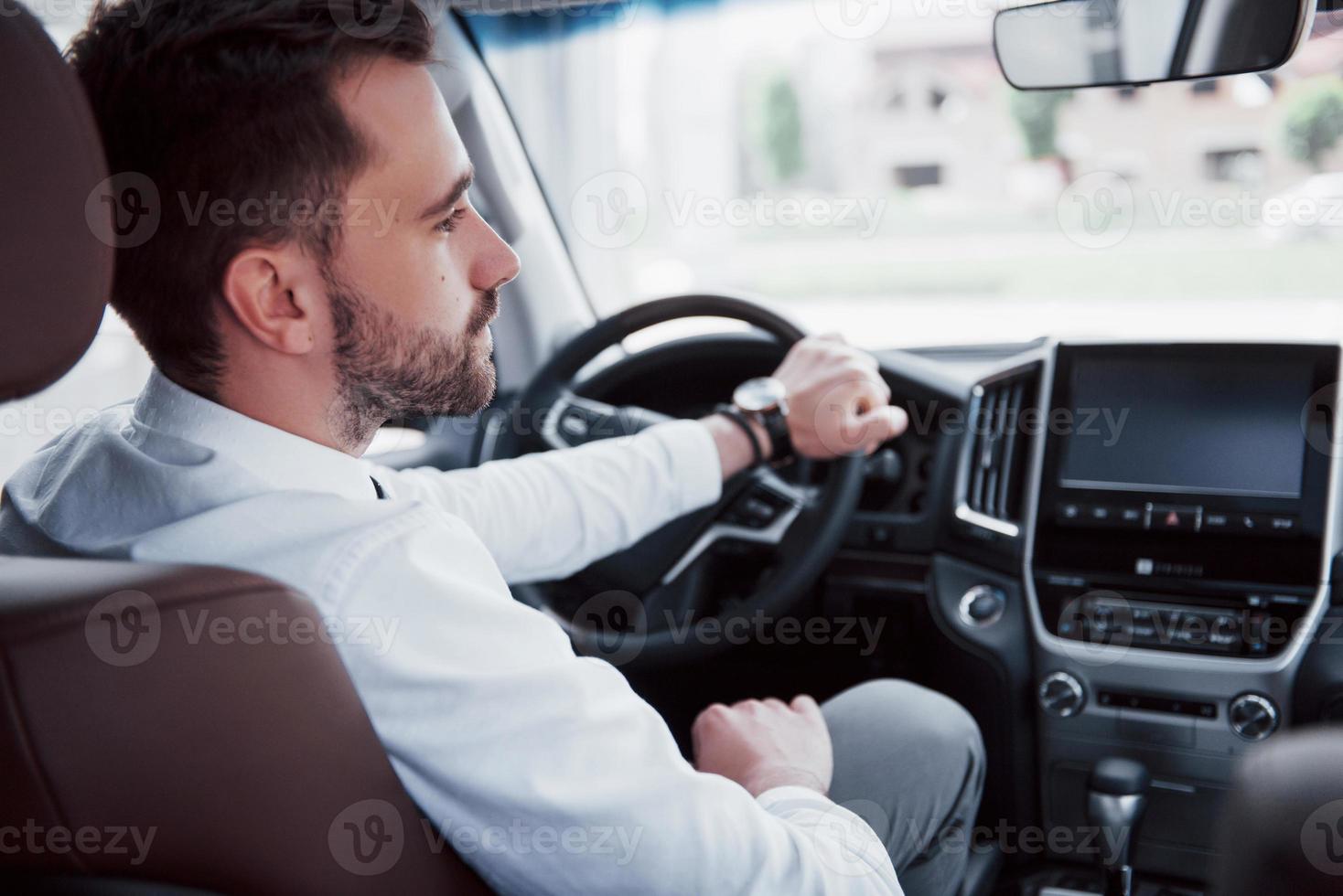 jovem empresário confiante sentado ao volante de seu novo carro foto