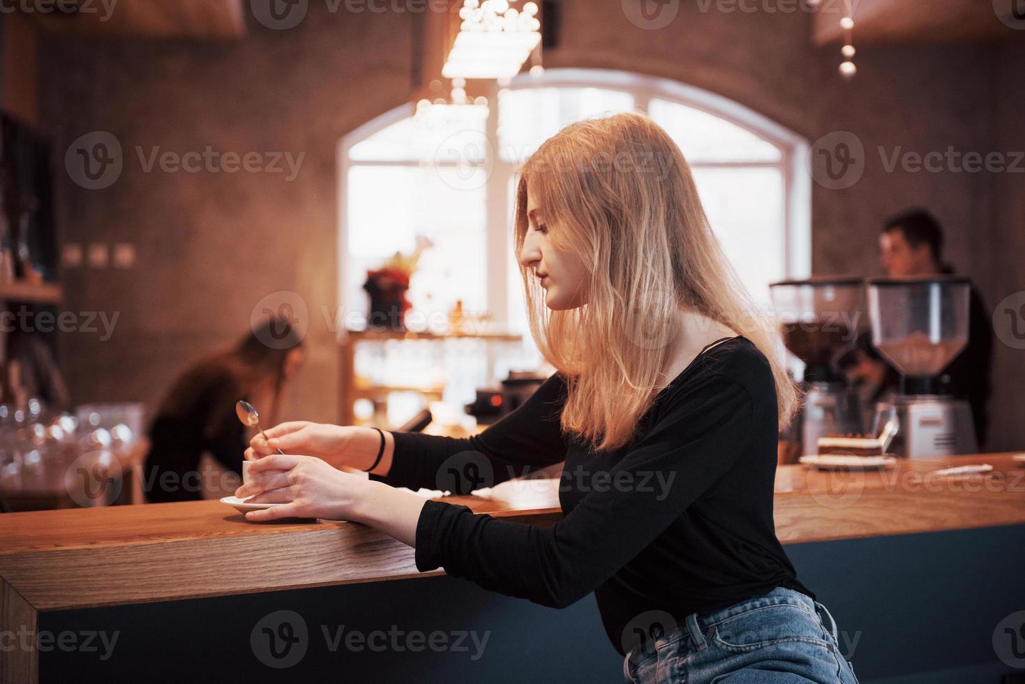 mulher jovem sorridente feliz usando telefone em um café. linda garota nas cores da moda da primavera foto