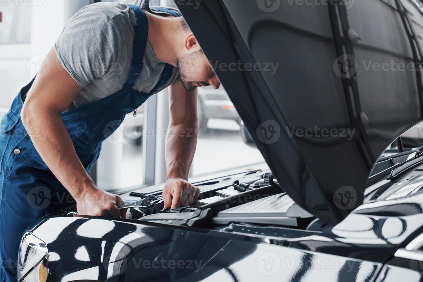 mãos do mecânico verificando a facilidade de manutenção do carro com o capô aberto, close-up. foto