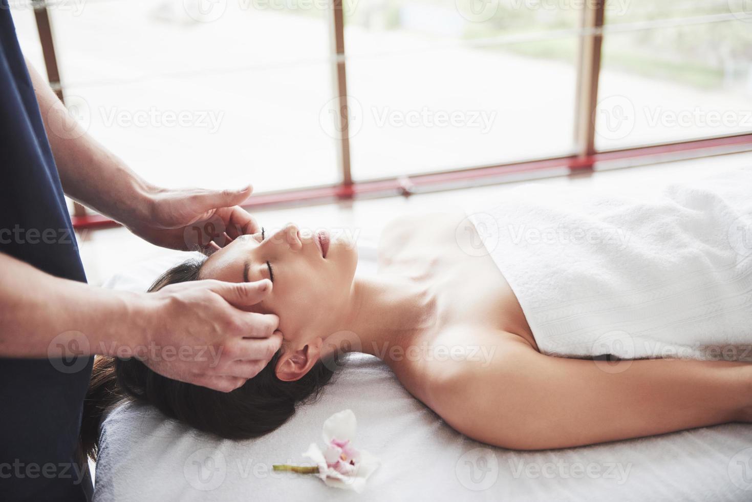 bela jovem relaxando com a massagem facial foto