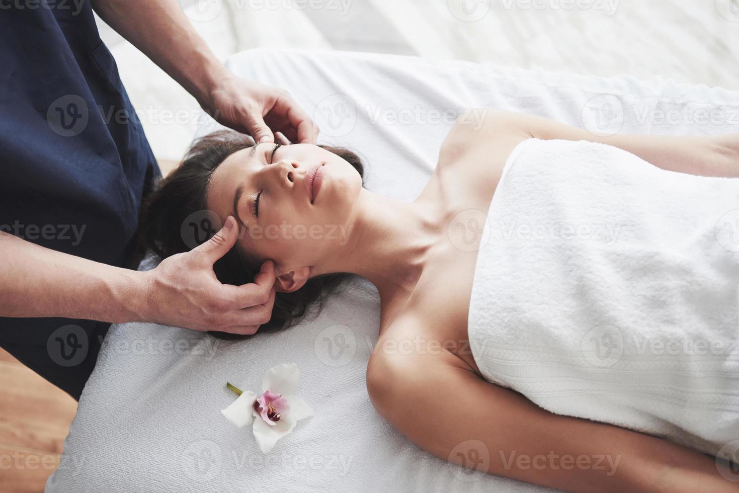 bela jovem relaxando com a massagem facial foto