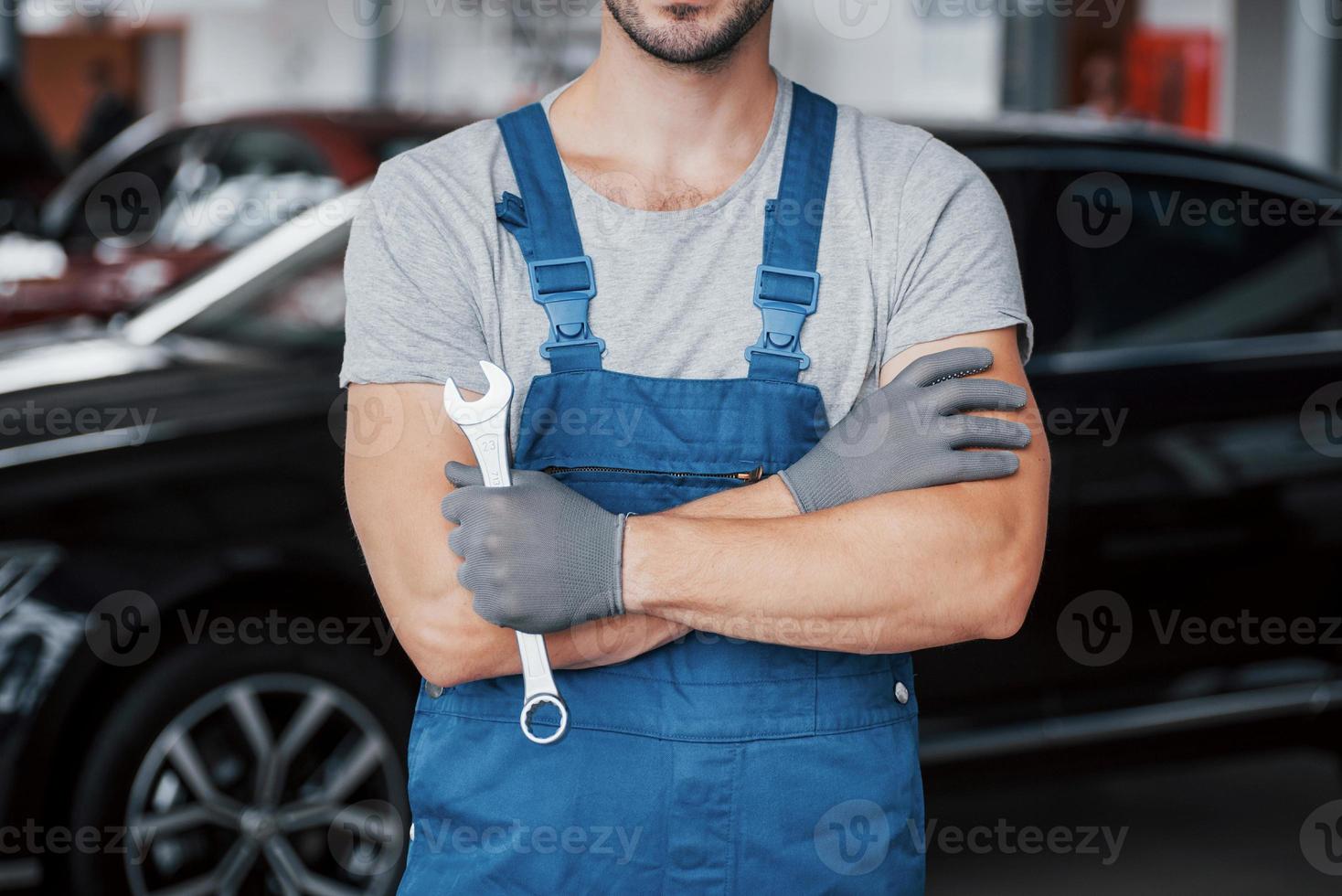 mãos do mecânico de automóveis com a chave inglesa na garagem foto