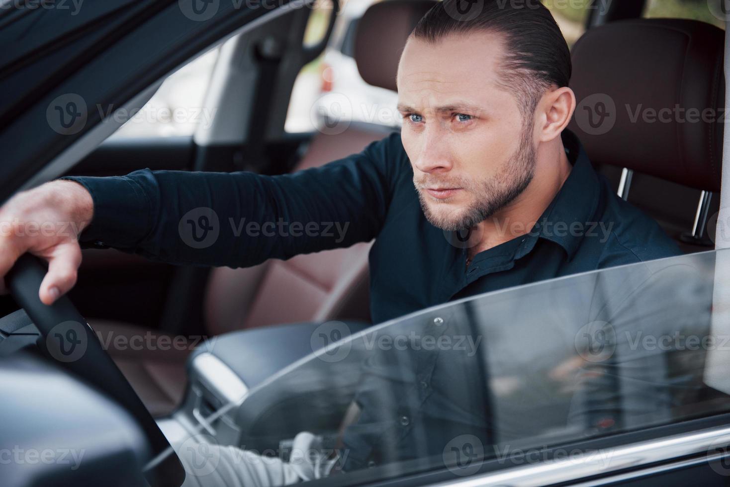 jovem empresário confiante sentado ao volante de seu novo carro foto