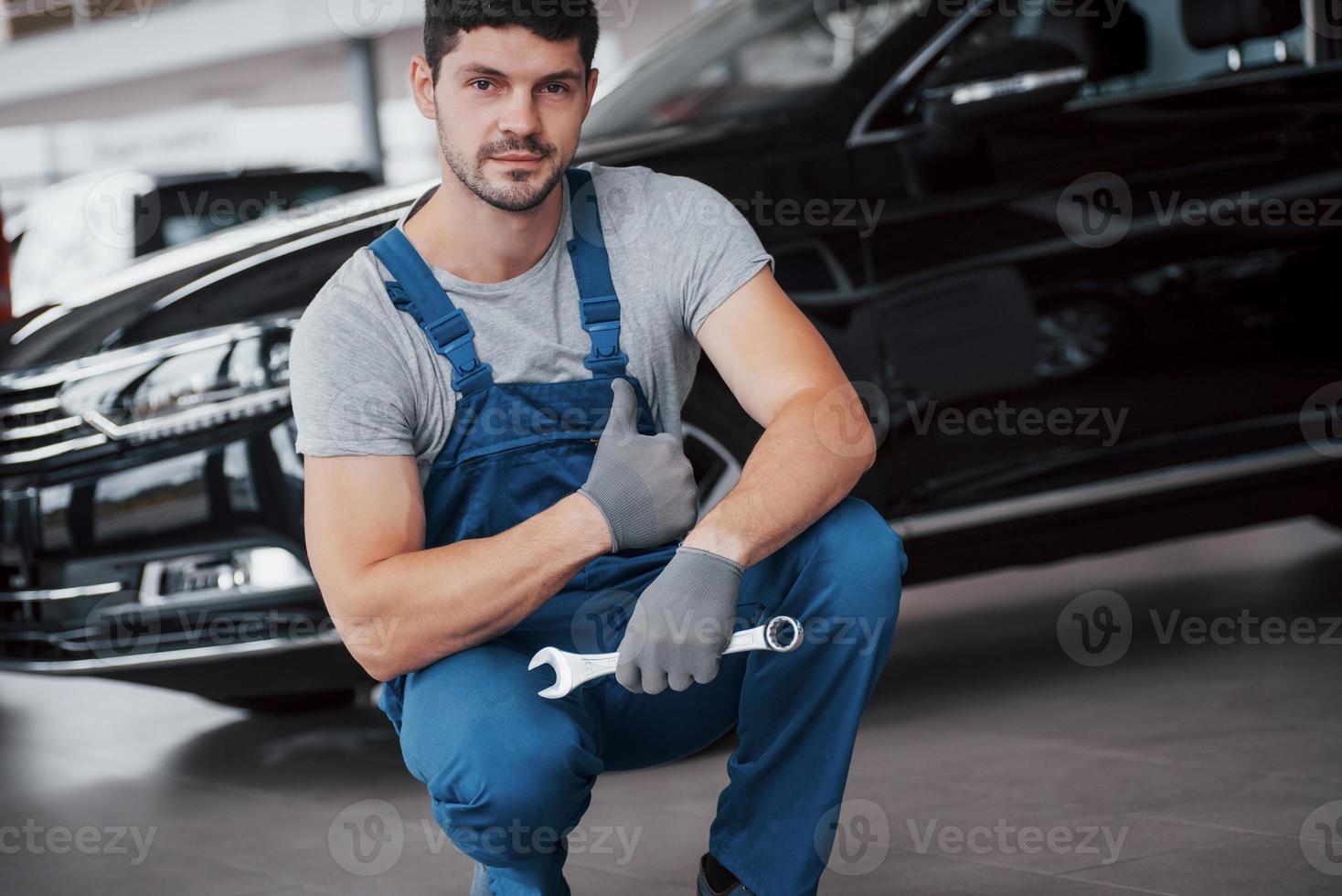 mãos do mecânico de automóveis com a chave inglesa na garagem foto