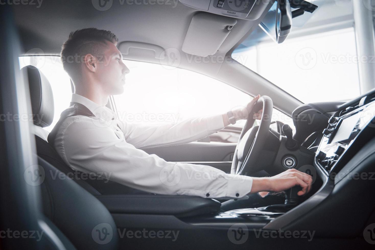 um jovem se senta ao volante em um carro recém-comprado, uma compra bem-sucedida. foto
