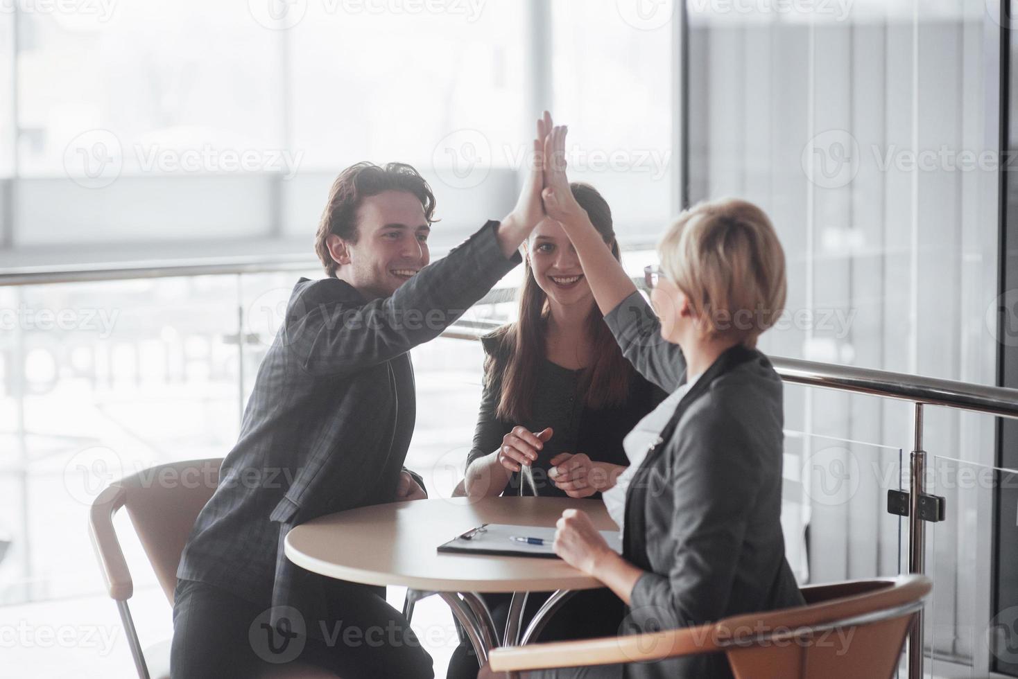 equipe de negócios de sucesso feliz dando um gesto de "high fives" enquanto riem e aplaudem seu sucesso foto
