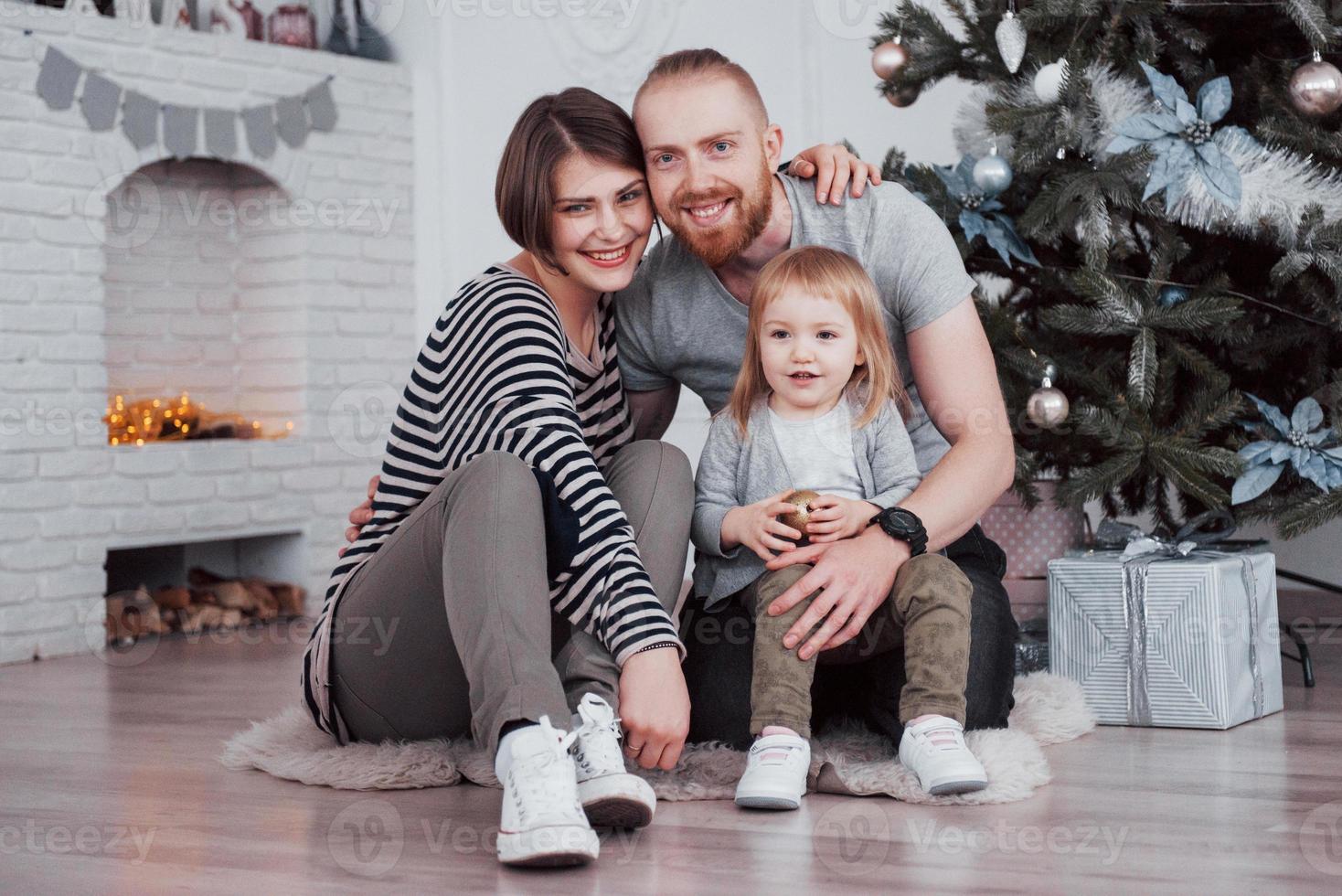 família feliz no natal de manhã abrindo presentes juntos perto do abeto foto