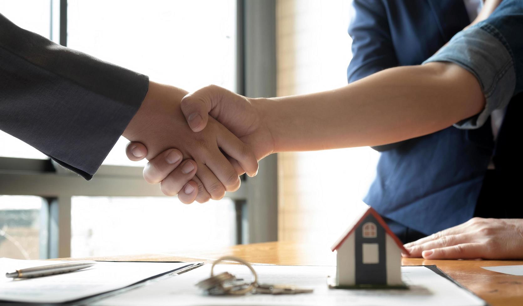 corretor de imóveis e cliente apertando as mãos após a assinatura de um conceito de seguro imobiliário, empréstimo à habitação e seguro foto
