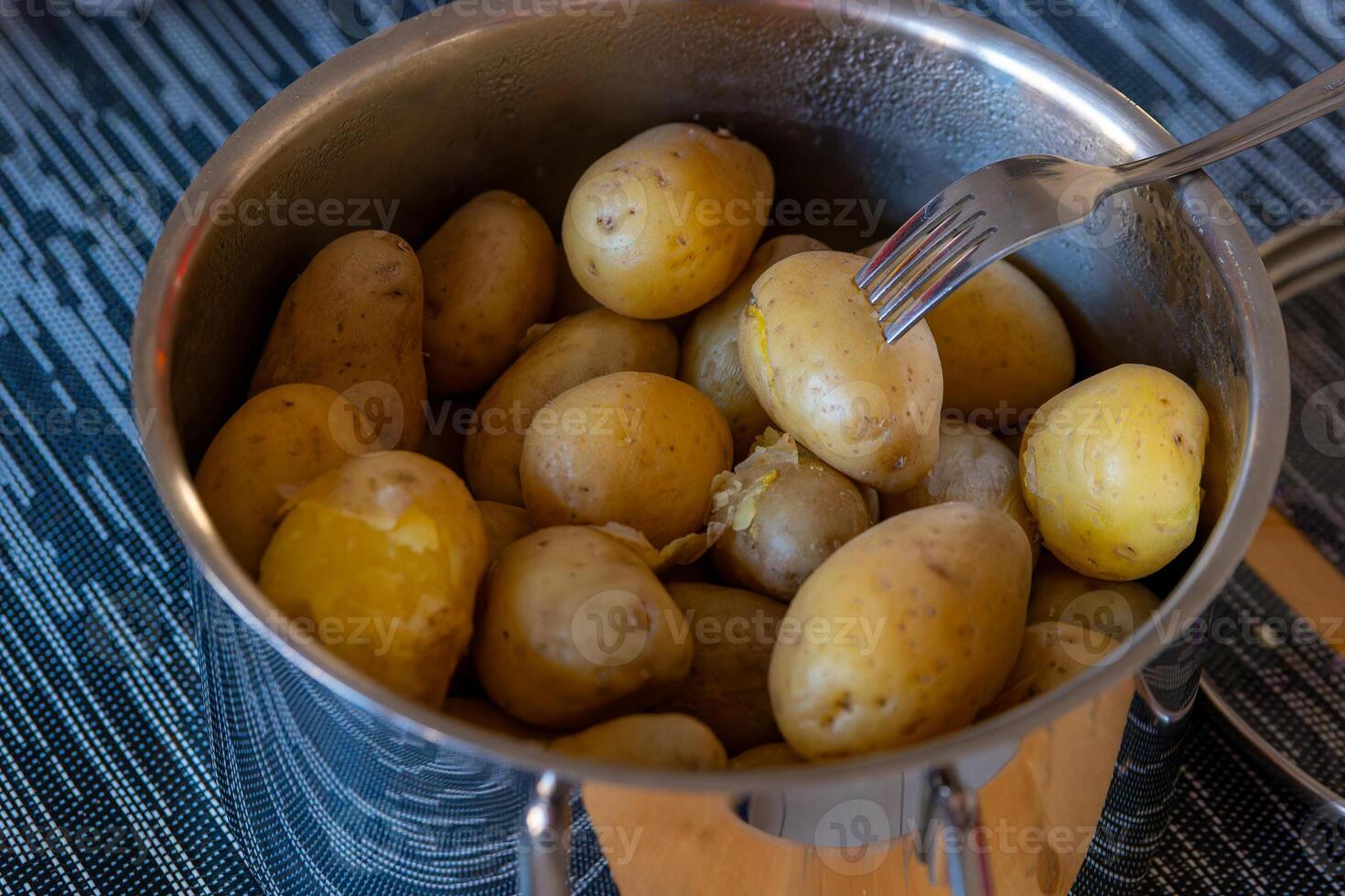 uma cozinhando Panela com com casca cozinhou batatas foto