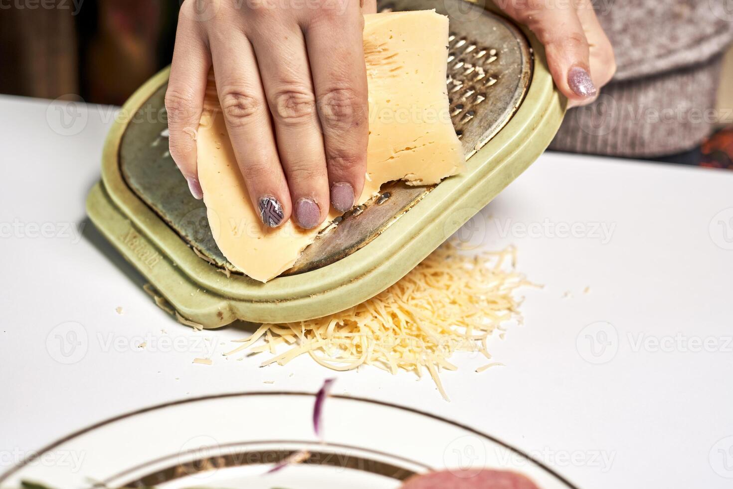 uma pessoa ralar queijo em uma prato foto