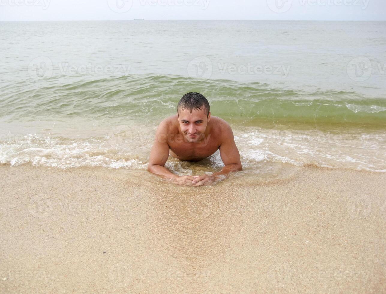 homem em a costa mentiras. a mar onda cobre a masculino. de praia foto