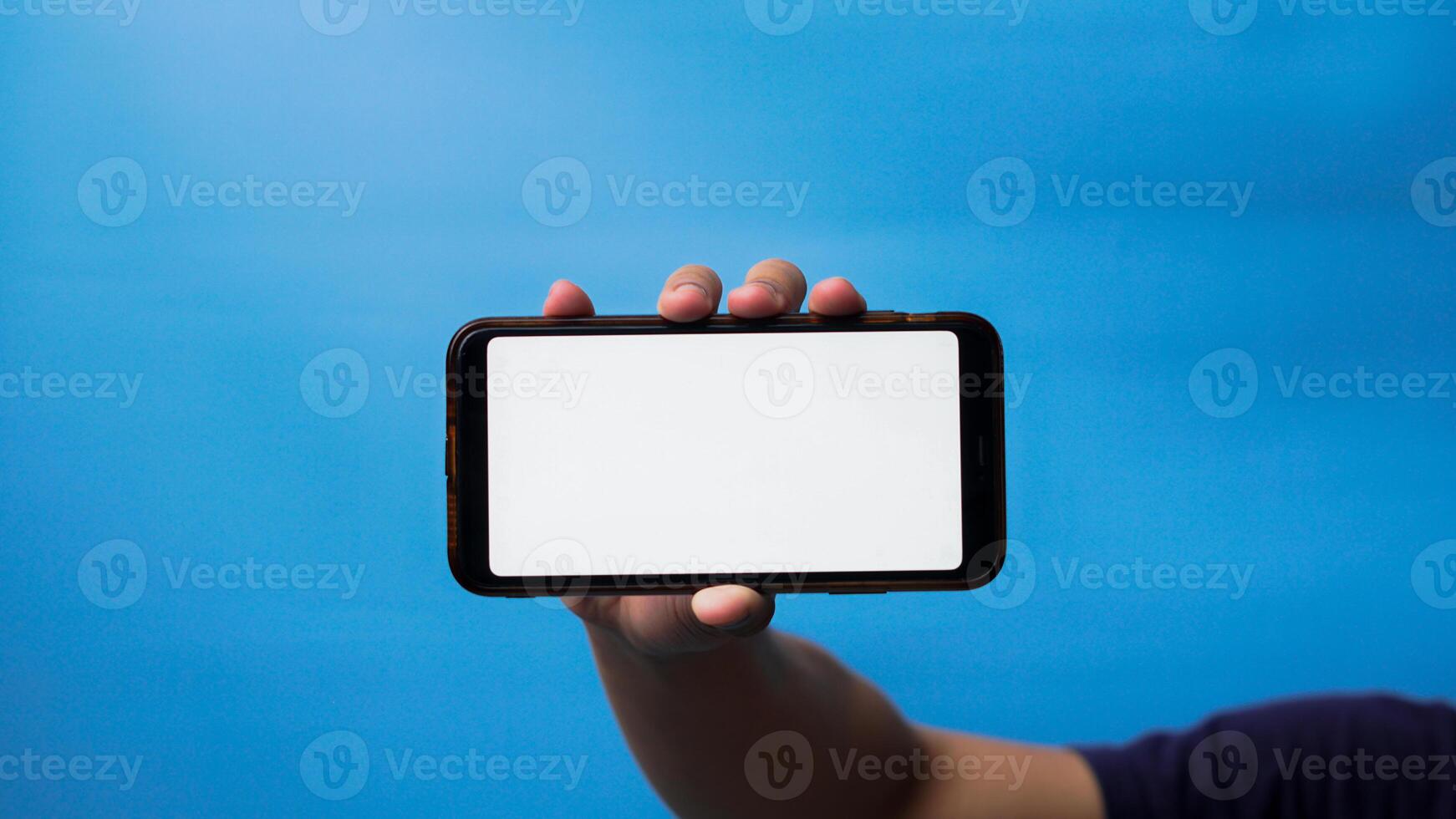 mão do homem segurando Móvel Smartphone e mostrando em branco telefone tela em azul fundo foto