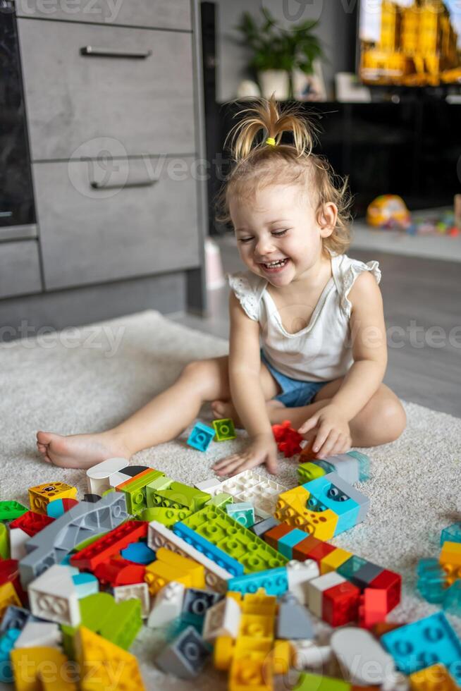 caucasiano criança uma pequeno menina é jogando dentro a construtor às lar. educacional brinquedos para crianças. foto
