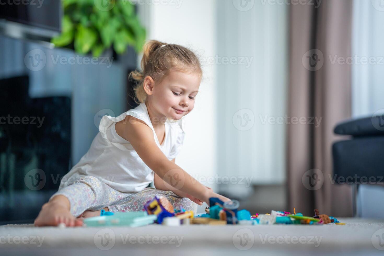 fofa pequeno menina tocam com pequeno construtor brinquedo em chão dentro lar, educacional jogo, gastos lazer Atividades Tempo conceito foto