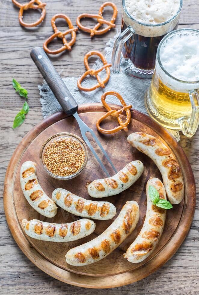 grelhado salsichas com salgadinhos e canecas do Cerveja foto