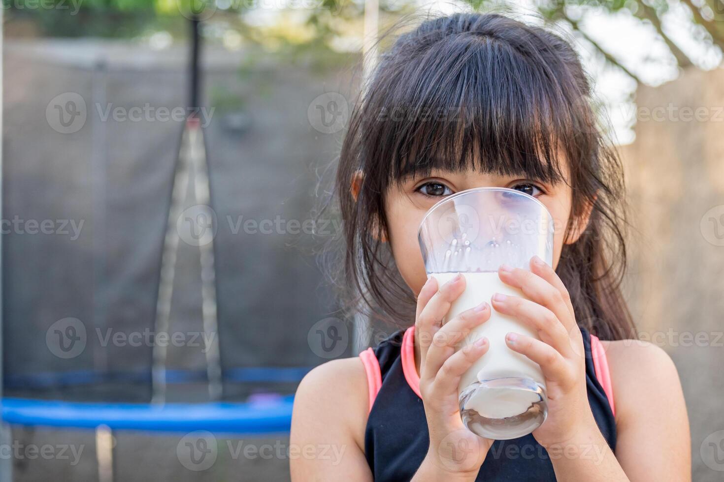 fechar-se retrato do dela. ela bebidas uma vidro do frio leite depois de jogando lado de fora dela casa. foto