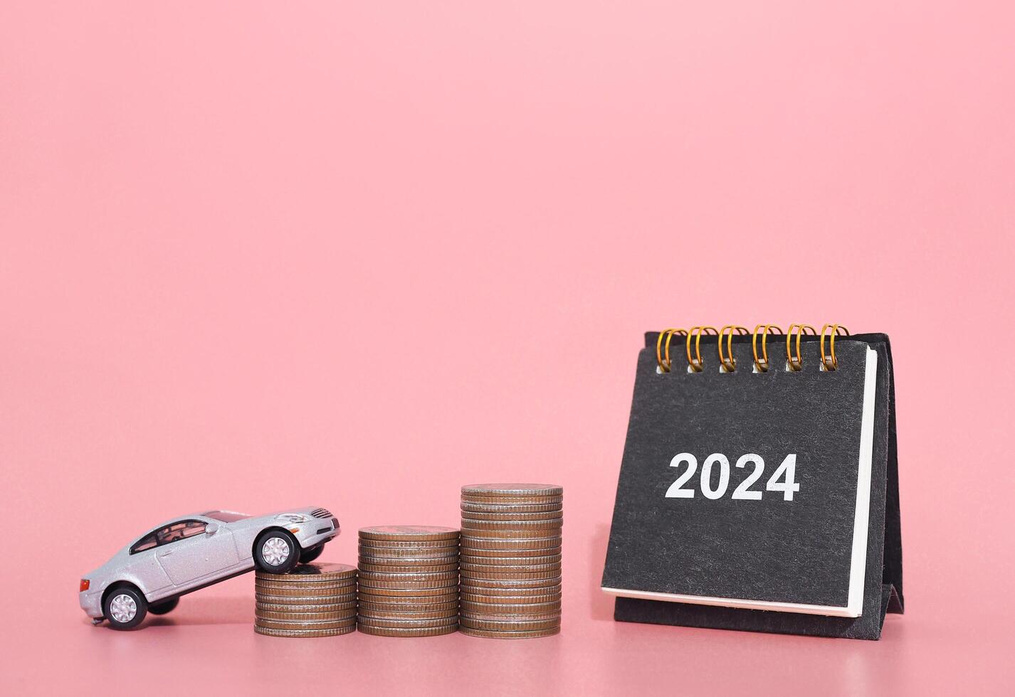 2024 escrivaninha calendário, brinquedo carros em pilha do moedas. a conceito do salvando dinheiro e gerir para sucesso transporte o negócio dentro ano 2024 foto