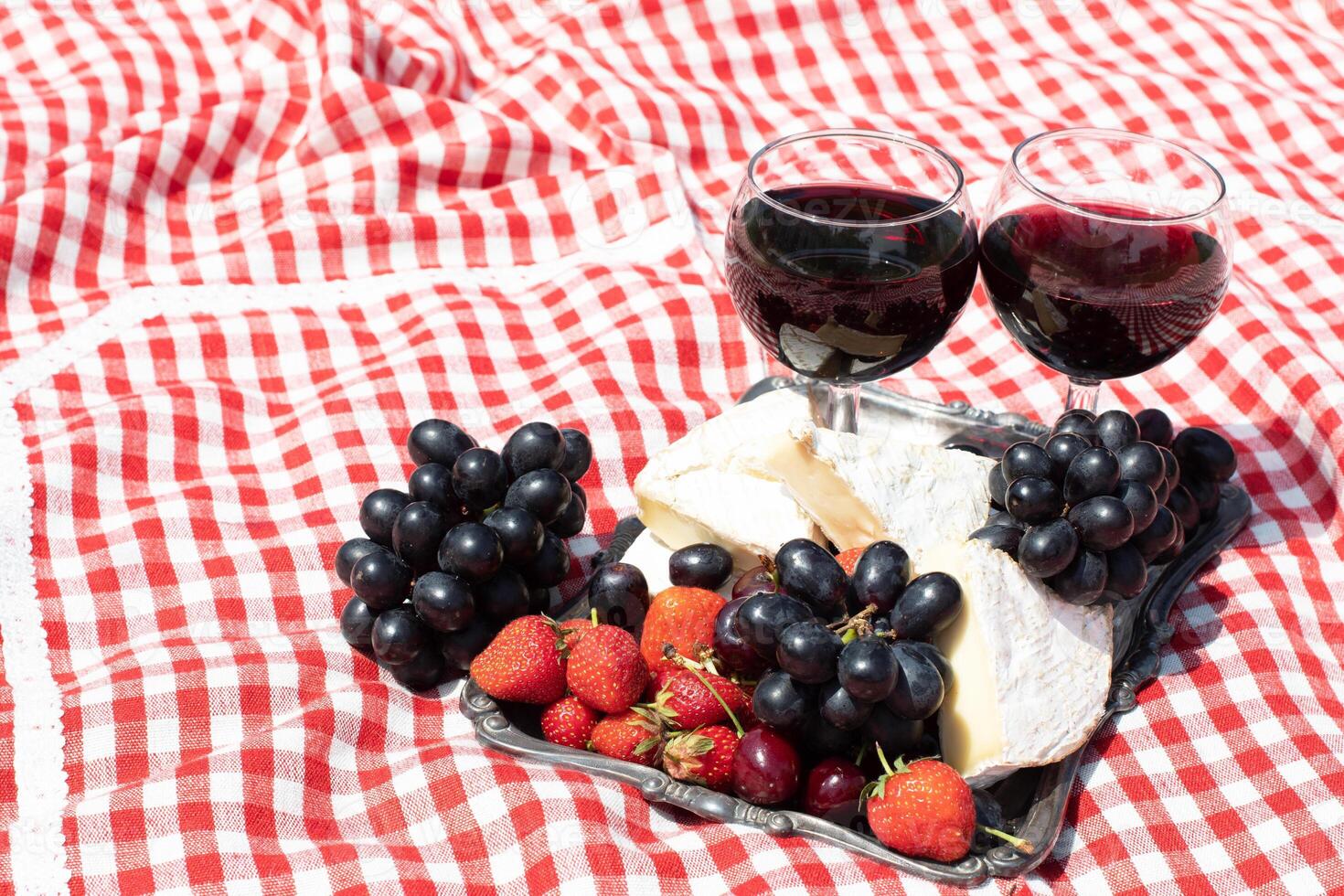 verão piquenique em uma verde gramado com vermelho vinho, queijo e fresco bagas, uvas foto