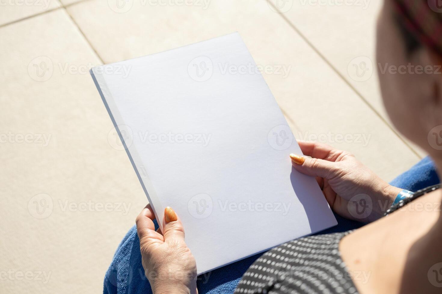 irreconhecível mulher segurando em branco revista para brincar projeto, sentado de a natação piscina foto