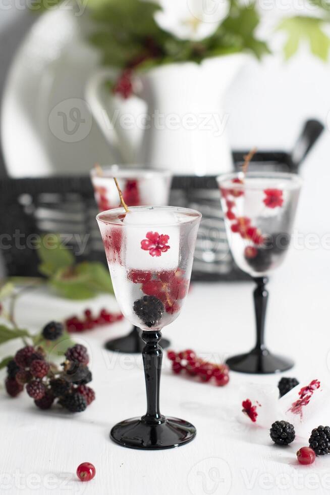 transparente Gin e tônico com gelo e fresco vermelho groselhas e Amora silvestre foto