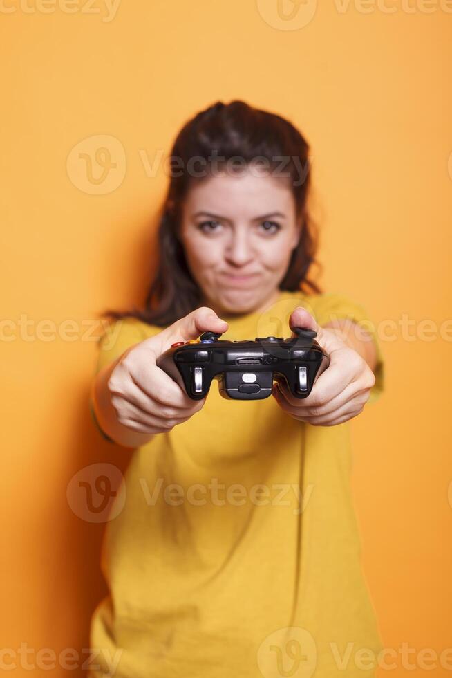 fechar-se do fêmea jogador usando controle de video game em console dentro frente do Câmera. focado mulher segurando controlador e jogando vídeo jogos com tecnologia, em pé sobre isolado fundo. foto