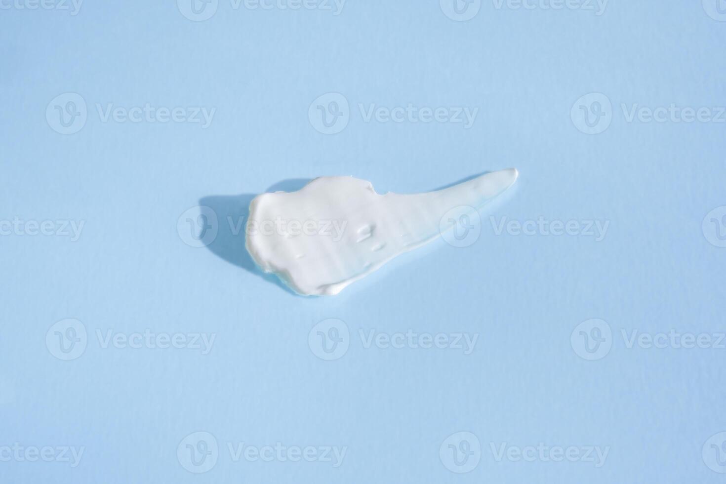 mancha branca de creme cosmético em um fundo azul. textura de base cremosa isolada. uma mancha de creme facial. close-up de textura cremosa foto