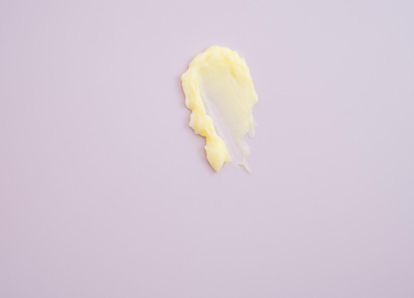 Cosmético produtos cremoso amarelo mancha textura em Rosa fundo. textura do natural cosméticos, cabelo mascarar, creme, esfregar foto