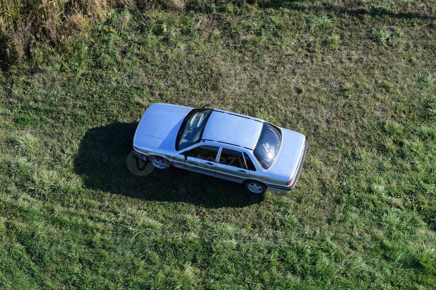 topo Visão do uma prata carro em pé em a grama. 1 voou sobre a carro. foto