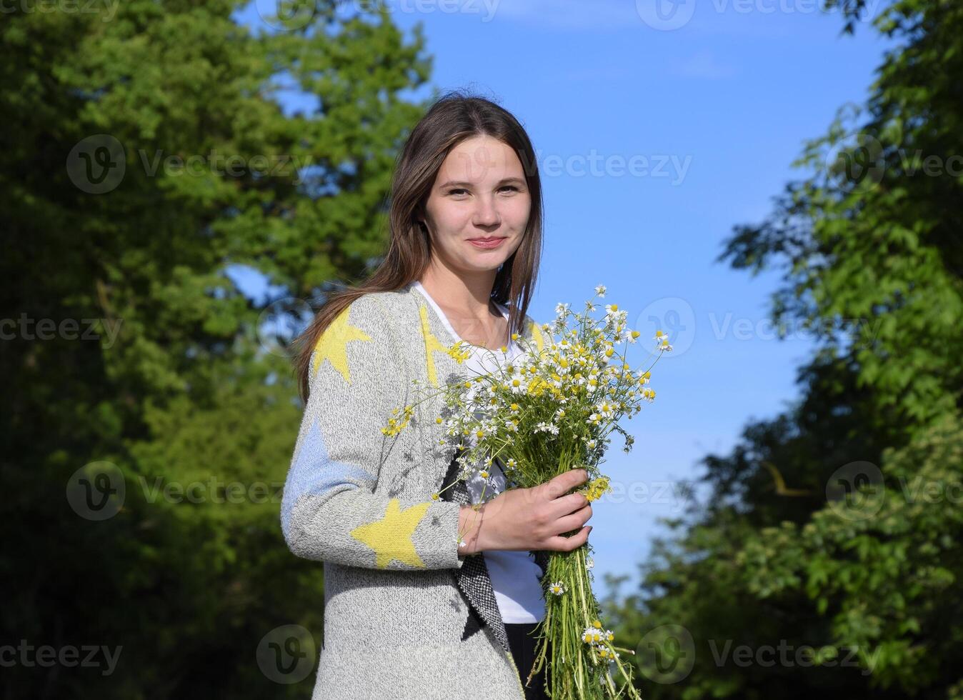 jovem lindo menina com uma ramalhete do camomilas. uma mulher dentro uma cevada campo foto