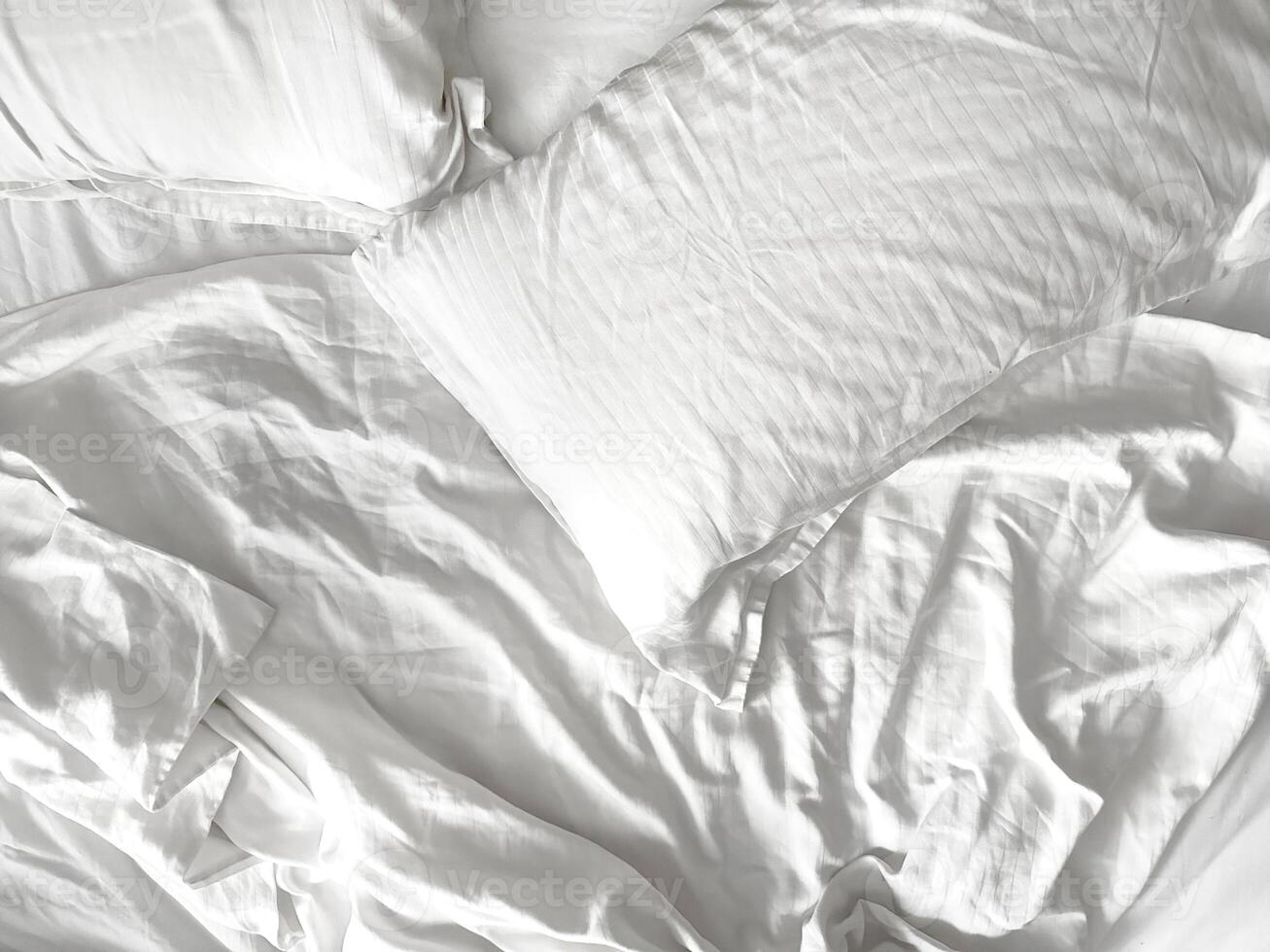 topo Visão do acolhedor roupa de cama folhas e travesseiro. branco listrado cetim cama linho. bagunça em cama. foto