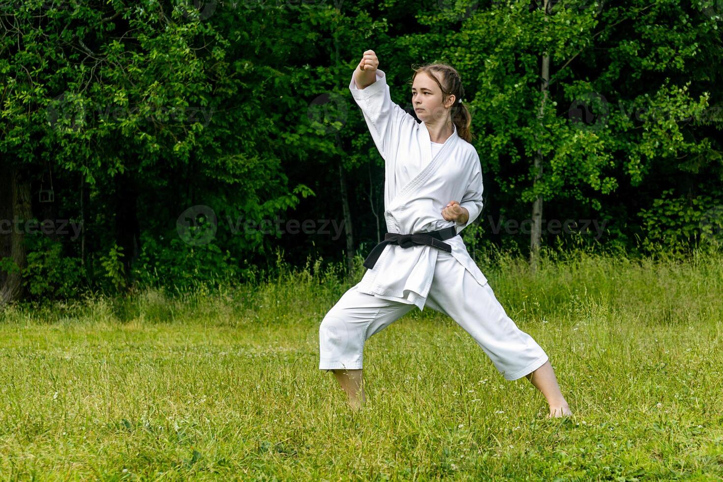 Adolescência menina Treinamento karatê kata ao ar livre, executa idade-uke Aumentar ou para cima quadra foto