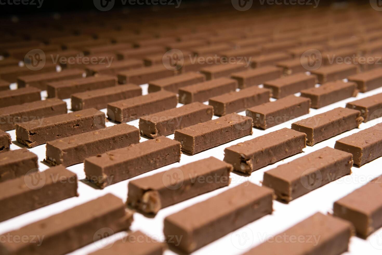 recheios para doces antes derramando com líquido chocolate em a transportador do uma confeitaria fábrica foto