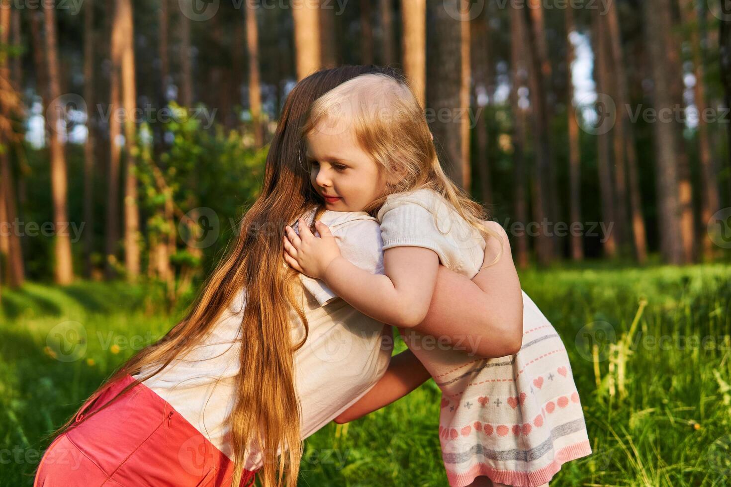 pequeno menina abraços dela mãe ao ar livre foto