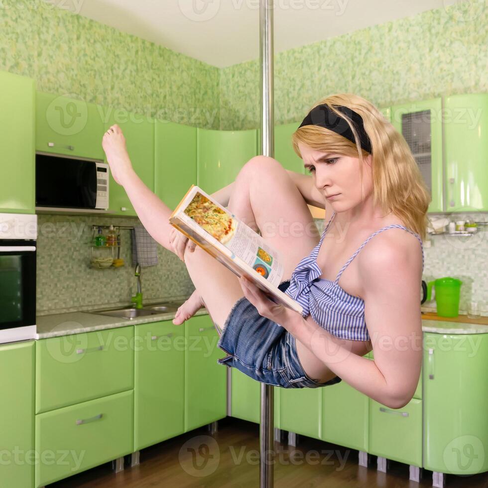 jovem mulher lê livro de receitas enquanto exercício dentro pólo dança às casa foto