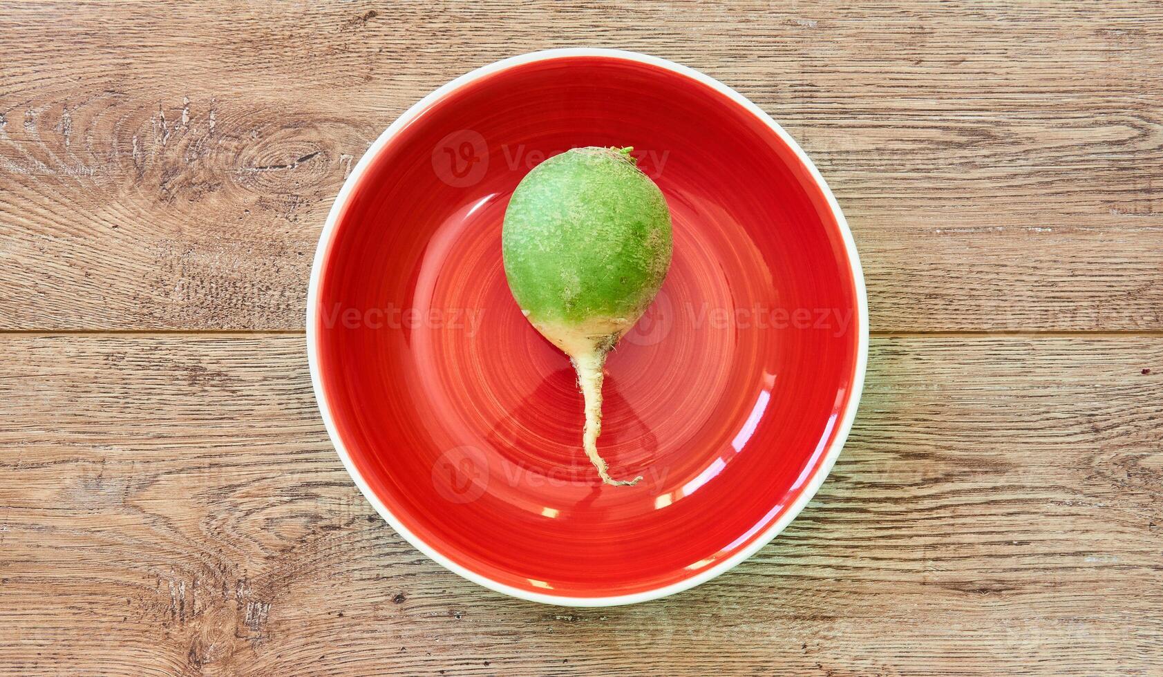 grande verde rabanete em uma vermelho prato em uma de madeira de mesa foto