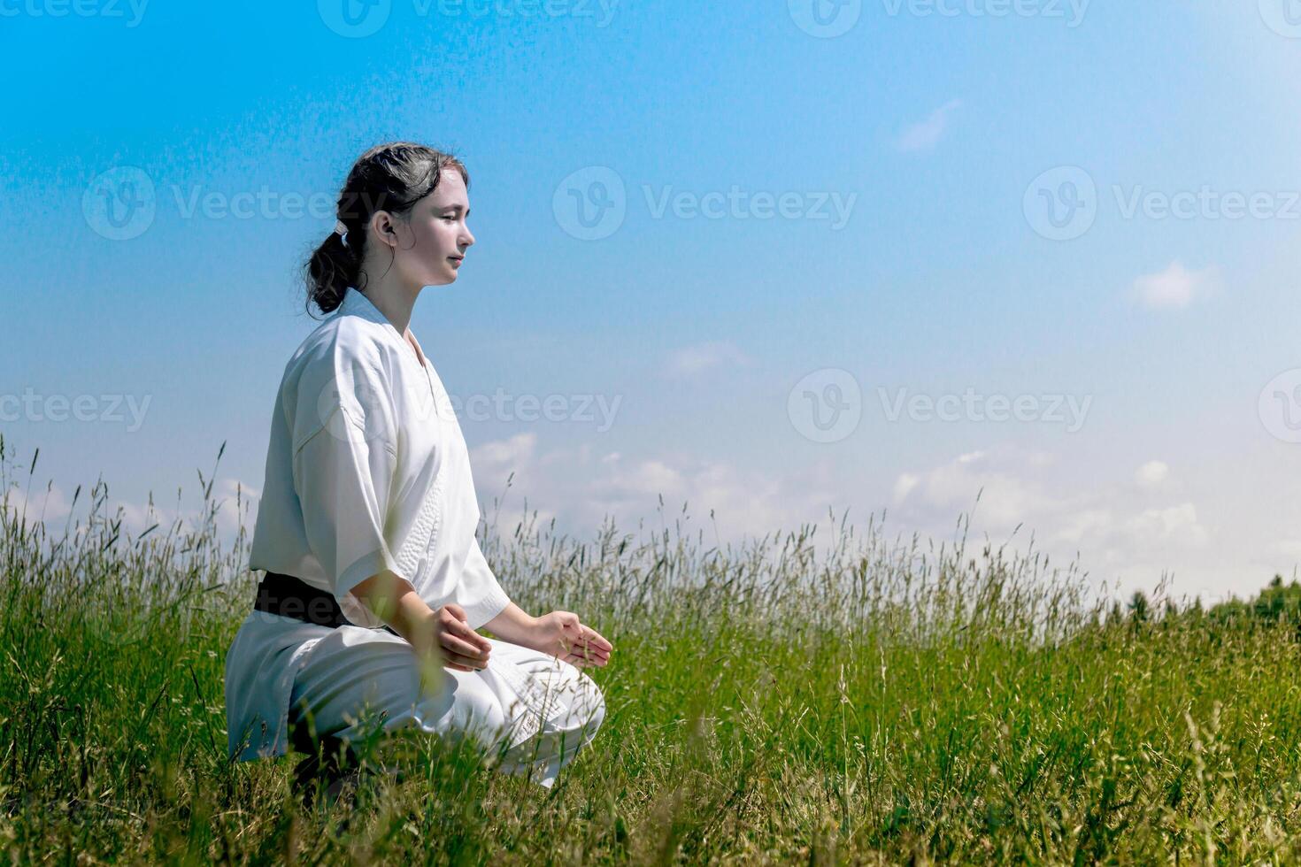 Adolescência menina carateca antes iniciando Treinamento ao ar livre entra a Mokuso meditativo Estado dentro a seiza pose foto