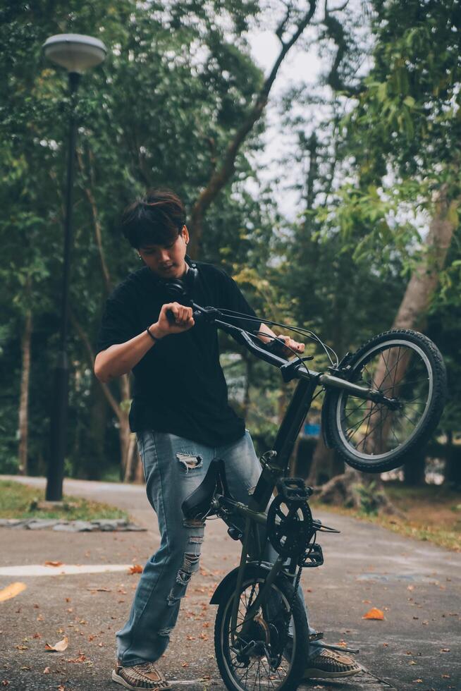 jovem bonito barbudo homem levando uma pausa enquanto viajando a cidade com dele bicicleta usando dele digital tábua olhando longe pensativamente foto