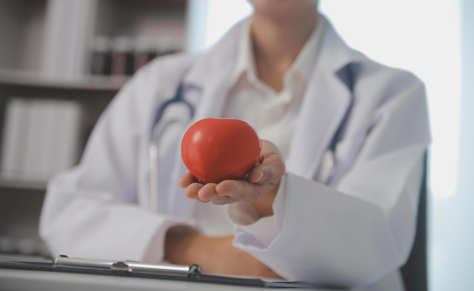 mãos do médico mulher segurando vermelho coração, mostrando símbolo do amor, humano Apoio, suporte para paciente, promovendo médico seguro, cedo checar para assistência médica, cardiologista ajuda. fechar acima do objeto foto