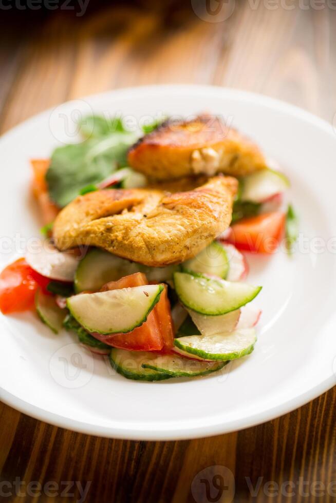 frito frango filé com fresco pepinos, tomates e rabanetes dentro uma prato foto