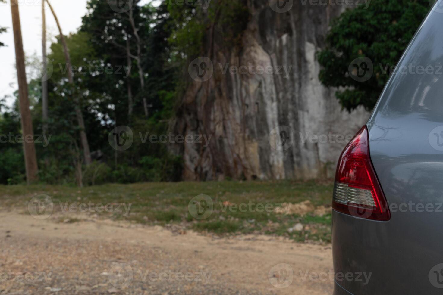 ao lado do cinzento carro pode Vejo rabo claro. estacionamento dentro a parque. fundo do sujeira estradas e Alto montanhas e florestas. foto