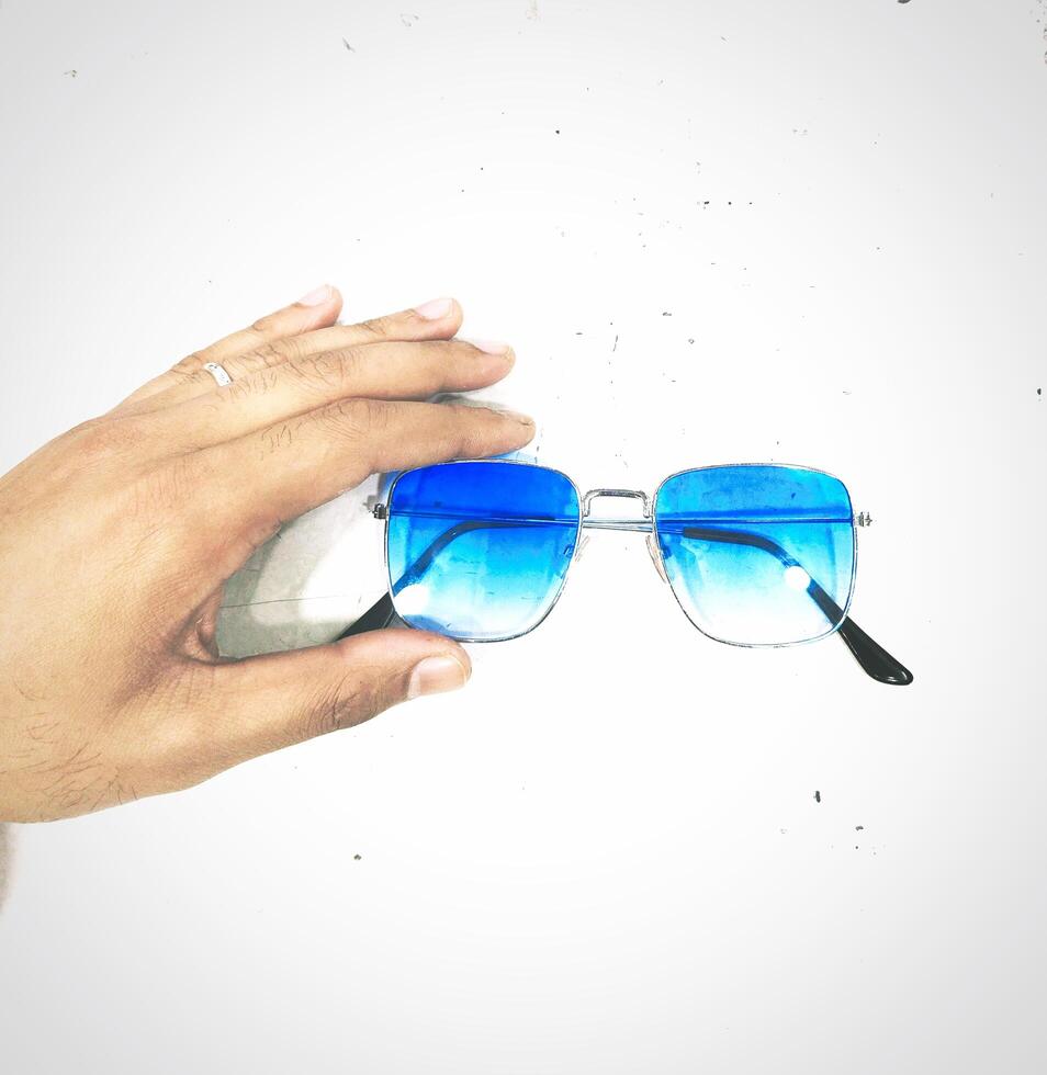 uma mão segurando uma par do azul oculos de sol foto