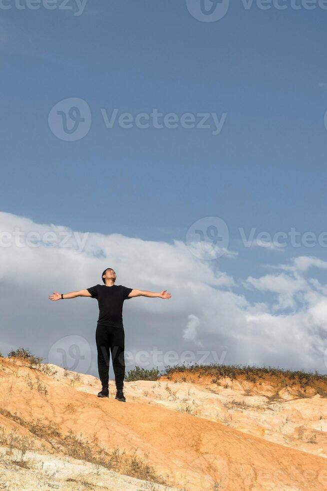 feliz homem espalhando dele mãos e olhando às a céu agradecendo em topo do a montanha com espaço para texto foto