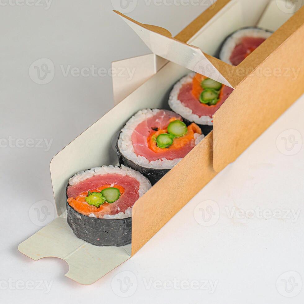 três Sushi rolos dentro uma cartão caixa em uma mesa foto