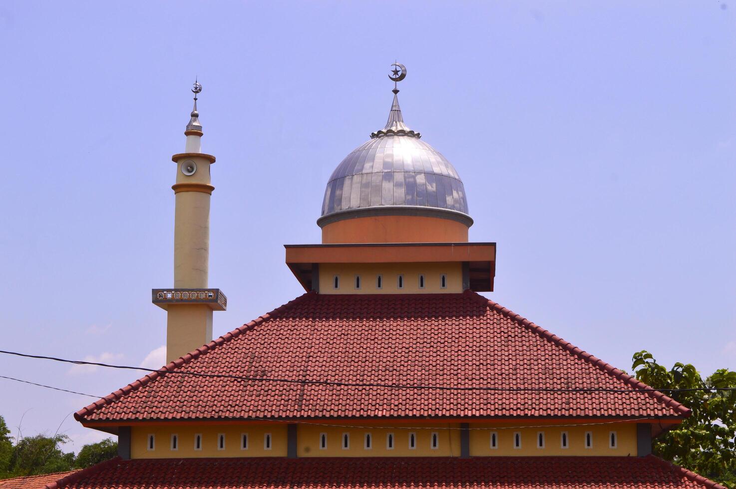 mesquita com uma brilhando prata cúpula e vermelho teto, em destaque contra uma Claro céu foto