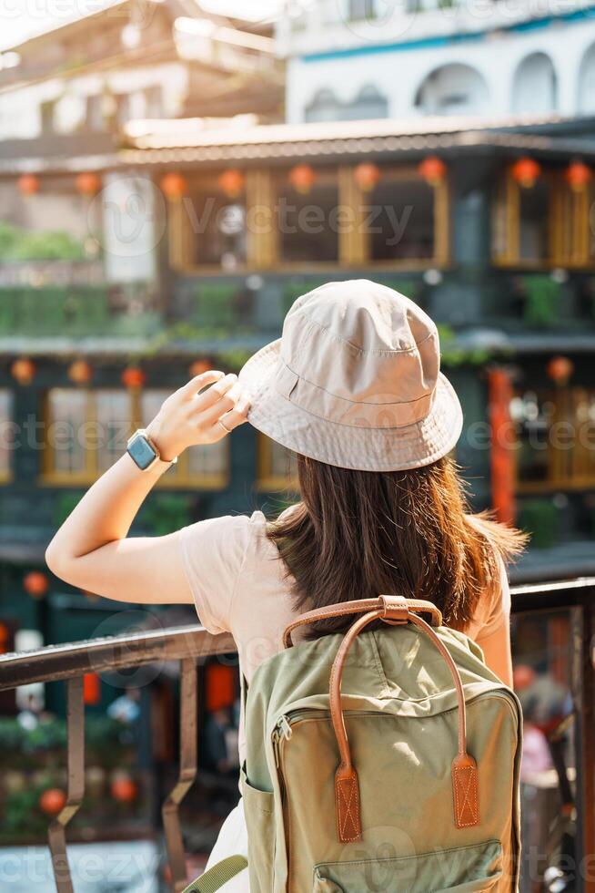 mulher viajante visitando dentro Taiwan, turista com chapéu e mochila passeios turísticos dentro Jiufen velho rua Vila com chá casa fundo. ponto de referência e popular atrações perto Taipei cidade. viagem conceito foto