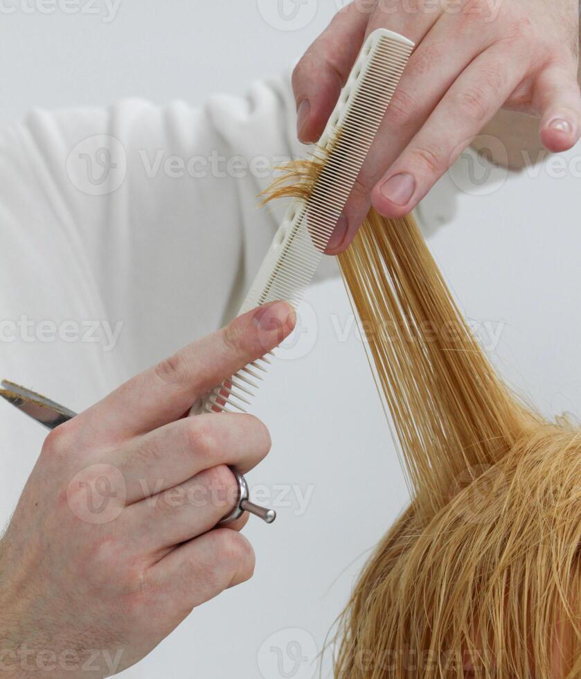 mãos do invisível cabeleireiro com tesouras e pente que detém uma vertente do a do cliente cabelo. seletivo foco.alto qualidade foto