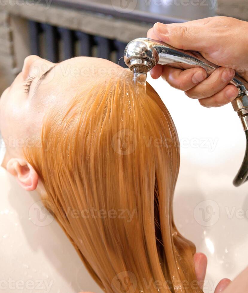 cabeleireiro detém rega e água água derrama a cabelo do a cliente dentro a beleza salão. Alto qualidade foto