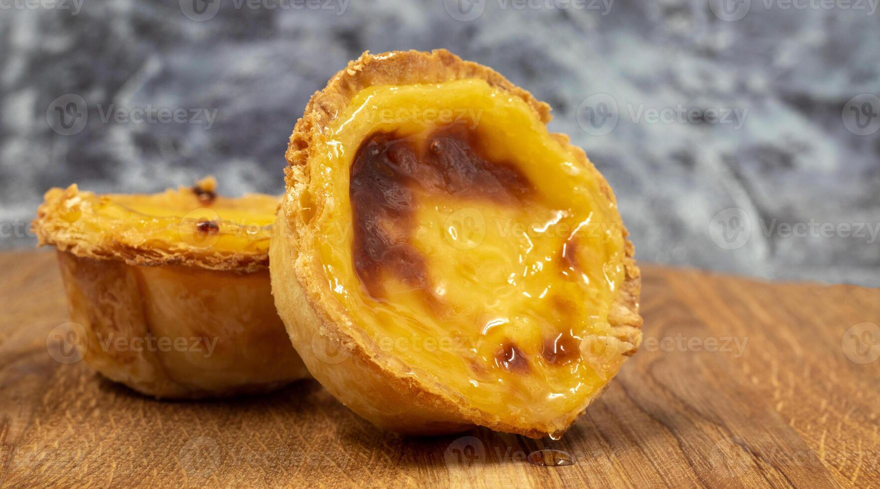 pastel de nata tortas ou Português ovo azedo em uma de madeira Castanho fundo. pastel de belém é uma pequeno torta com uma crocantes sopro pastelaria crosta e uma creme creme enchimento. doce sobremesa. foto